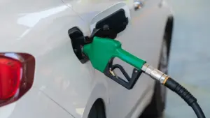 Degvielas uzpildes pistole ievietota baltas automašīnas degvielas tvertnē degvielas uzpildes stacijā.