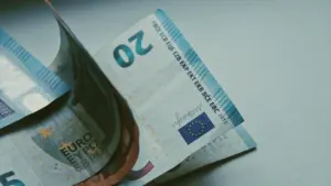 Piecu eiro banknote uz balta galda, simbolizējot Latvijas valsts budžeta un ekonomikas tēmas.