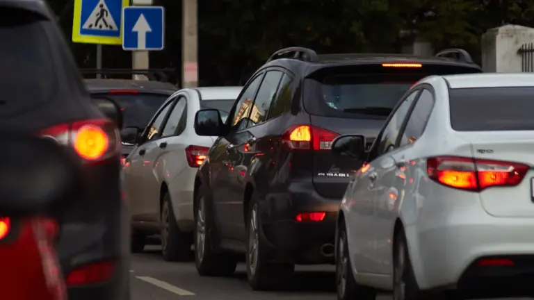 Automašīnas Rīgas ielās stāv sastrēgumā, gaidot zaļo luksofora signālu satiksmē.