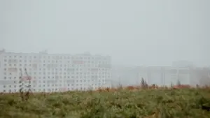 Balta daudzstāvu ēka miglainā rudens rītā Rīgā, atgādinot par tuvojošos aukstumu.