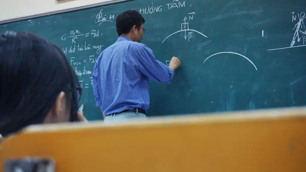 Skolotājs raksta fizikas formulas uz tāfeles klases priekšā mācību stundas laikā